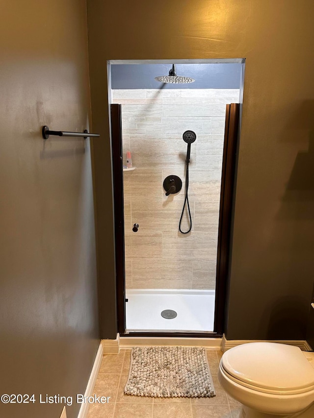 bathroom with a tile shower, toilet, and tile patterned floors