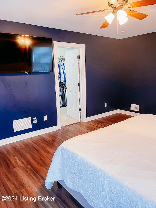 bedroom with a spacious closet, ceiling fan, a closet, and hardwood / wood-style flooring