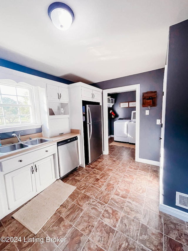 kitchen featuring washing machine and clothes dryer, white cabinetry, appliances with stainless steel finishes, and sink