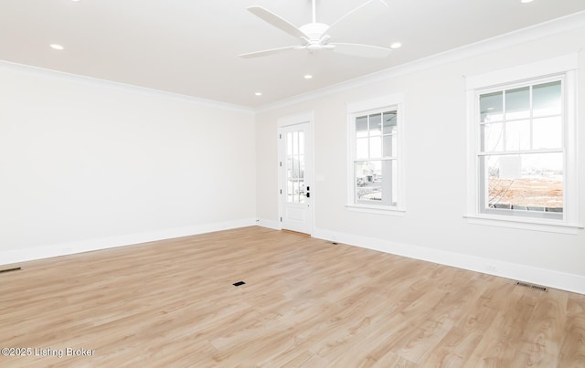 empty room with ornamental molding, a wealth of natural light, ceiling fan, and light hardwood / wood-style flooring