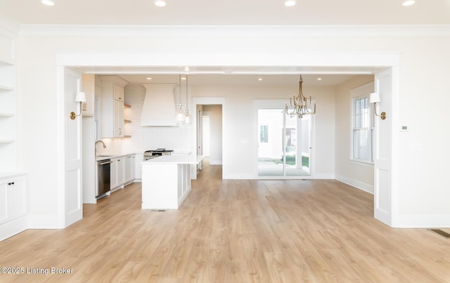 kitchen featuring wall chimney range hood, white cabinetry, hanging light fixtures, stainless steel appliances, and decorative backsplash