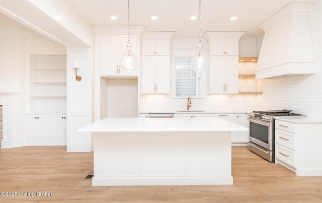 kitchen featuring white cabinetry, sink, stainless steel stove, and a kitchen island