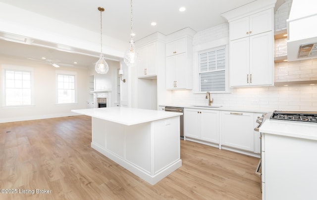 kitchen with stainless steel dishwasher, sink, a kitchen island, and white cabinets