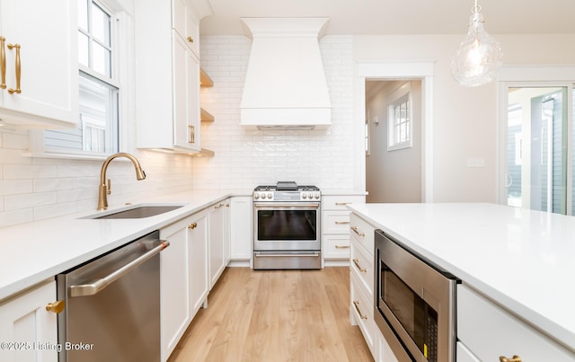 kitchen with stainless steel appliances, sink, custom exhaust hood, and white cabinets