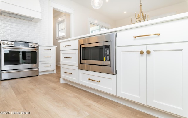 kitchen featuring white cabinetry, custom range hood, and appliances with stainless steel finishes