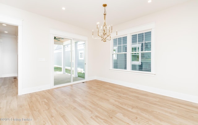 empty room with a notable chandelier and light hardwood / wood-style floors