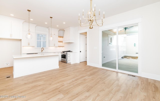 kitchen featuring premium range hood, stainless steel range, a kitchen island, and white cabinets