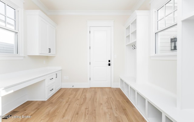 mudroom featuring built in desk, ornamental molding, and light wood-type flooring