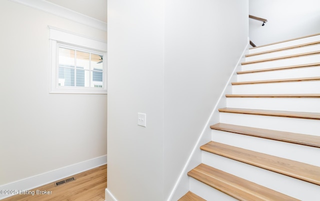 stairs with hardwood / wood-style flooring and ornamental molding