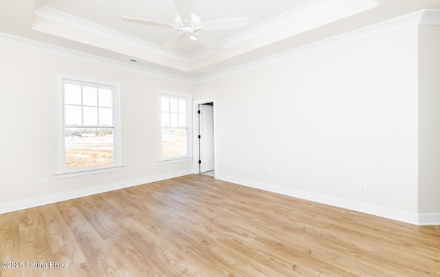 empty room featuring crown molding, ceiling fan, light hardwood / wood-style floors, and a tray ceiling