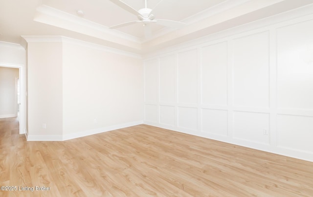 spare room with a raised ceiling, crown molding, ceiling fan, and light hardwood / wood-style floors