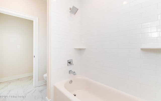 bathroom featuring toilet and tiled shower / bath