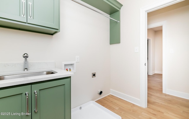 laundry area featuring sink, light hardwood / wood-style flooring, electric dryer hookup, hookup for a washing machine, and cabinets