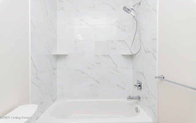 bathroom with tiled shower / bath combo and toilet