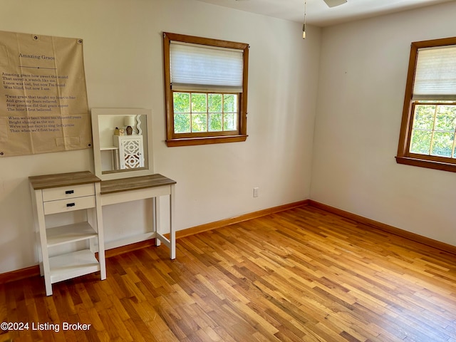 interior space with ceiling fan, multiple windows, and hardwood / wood-style floors