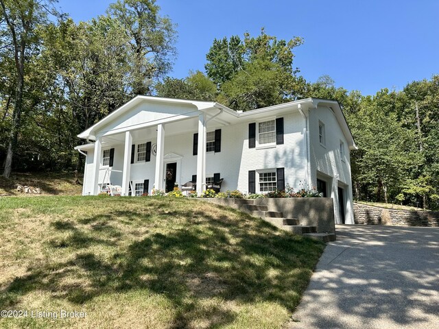 view of front of property with a front yard, a garage, and covered porch