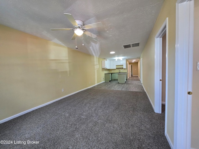 interior space with ceiling fan, carpet floors, and a textured ceiling