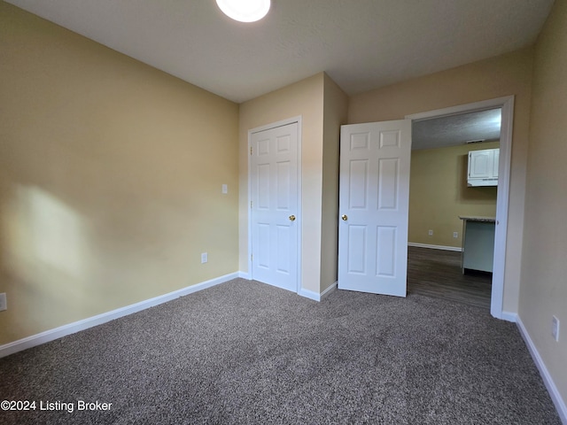 unfurnished bedroom with a textured ceiling and dark carpet