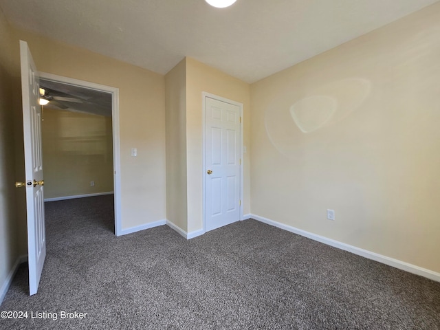 unfurnished bedroom with a closet and dark colored carpet