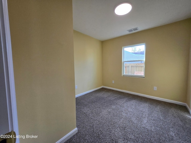 spare room featuring dark colored carpet