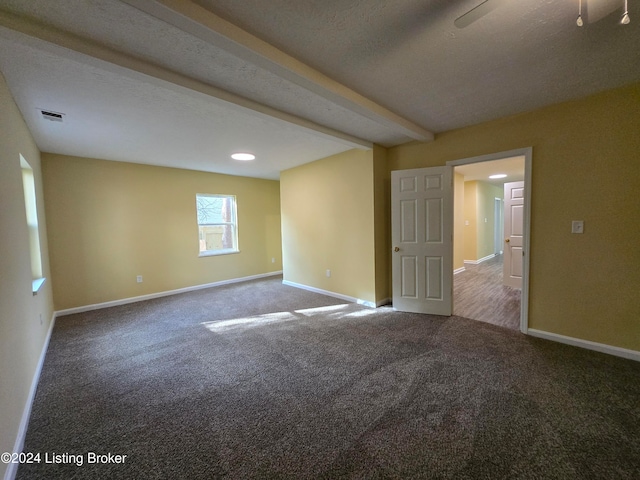 spare room featuring carpet flooring, a textured ceiling, and beamed ceiling