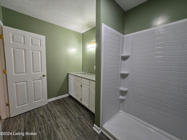 bathroom featuring vanity, a tile shower, wood-type flooring, and a textured ceiling