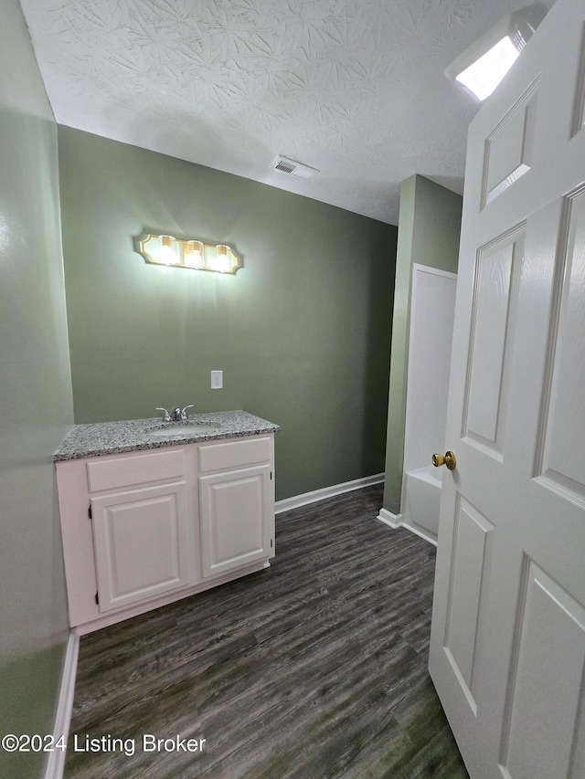 bathroom with a bathtub, vanity, a textured ceiling, and hardwood / wood-style flooring