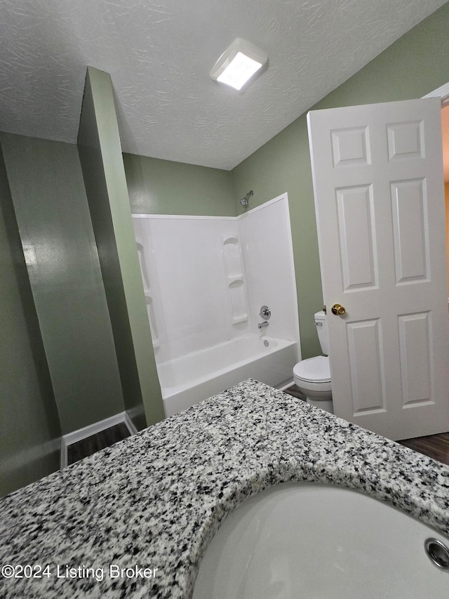 full bathroom featuring vanity, a textured ceiling, bathing tub / shower combination, wood-type flooring, and toilet