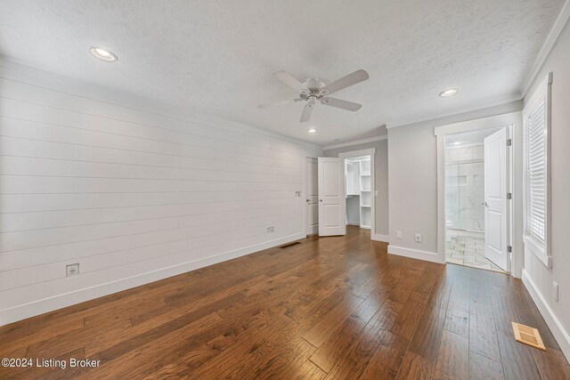 unfurnished bedroom featuring a textured ceiling, dark wood-type flooring, a walk in closet, ensuite bathroom, and ceiling fan