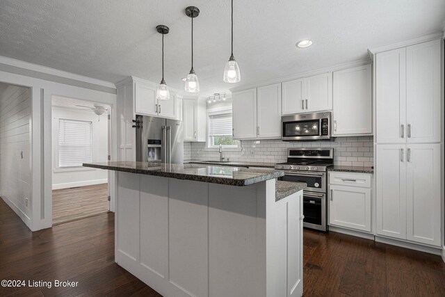 kitchen with white cabinetry, dark wood-type flooring, a kitchen island, stainless steel appliances, and sink