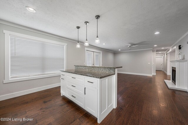 kitchen with dark stone counters, white cabinetry, hanging light fixtures, dark hardwood / wood-style flooring, and ceiling fan