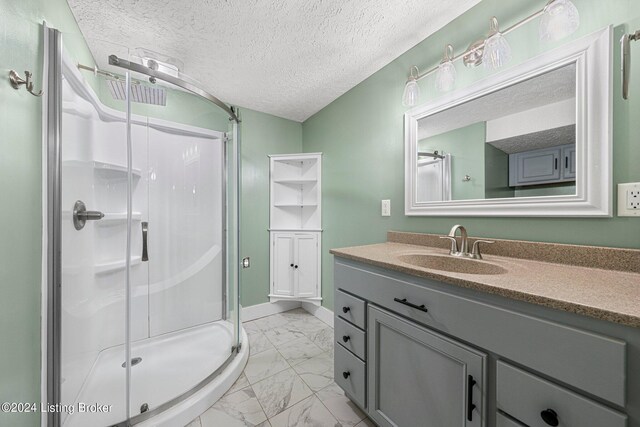 bathroom with a textured ceiling, a shower with door, and vanity