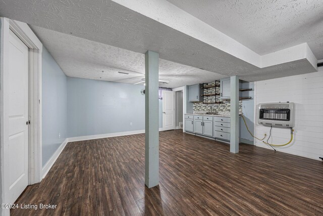 basement with a textured ceiling, dark hardwood / wood-style flooring, and heating unit