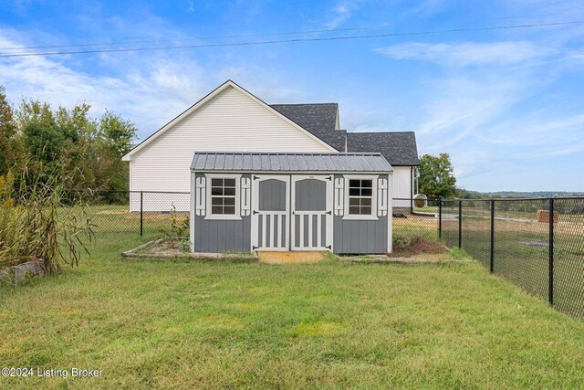 rear view of property featuring a storage shed and a yard