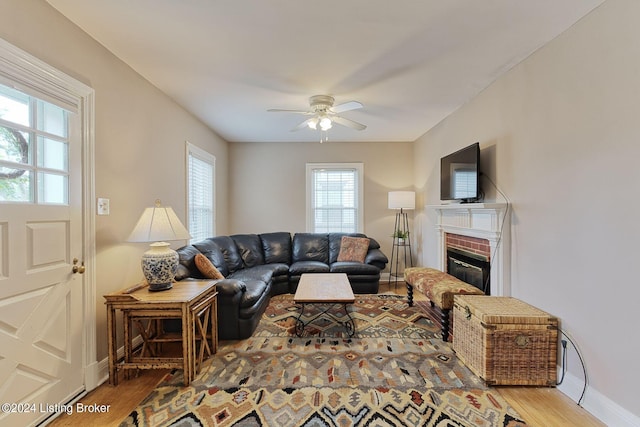 living room with a brick fireplace, ceiling fan, and hardwood / wood-style floors