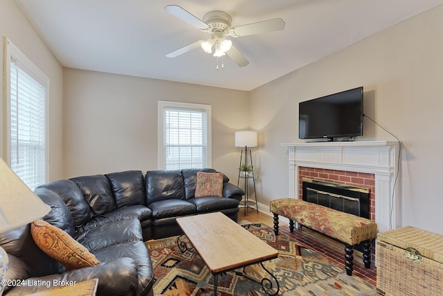 living room with ceiling fan, a brick fireplace, and wood-type flooring