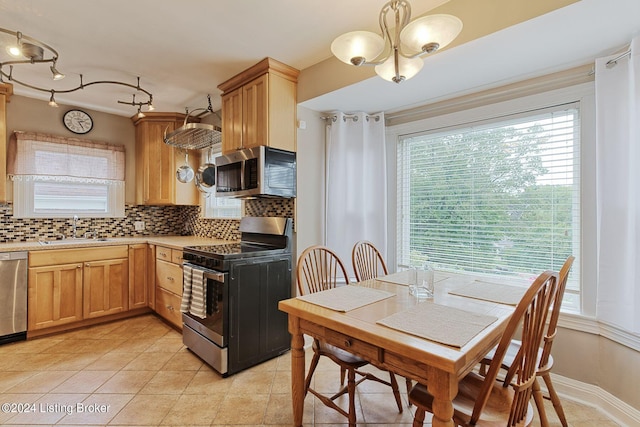 kitchen featuring tasteful backsplash, pendant lighting, stainless steel appliances, an inviting chandelier, and sink