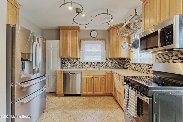 kitchen featuring light brown cabinetry, appliances with stainless steel finishes, sink, and tasteful backsplash