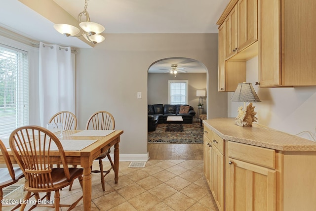 dining area with light wood-type flooring and ceiling fan with notable chandelier