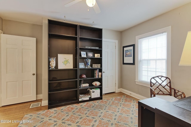 home office with light wood-type flooring and ceiling fan