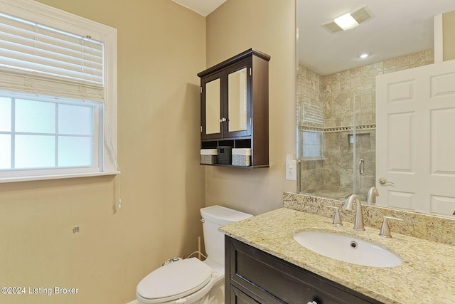 bathroom featuring vanity, a shower with shower door, and toilet