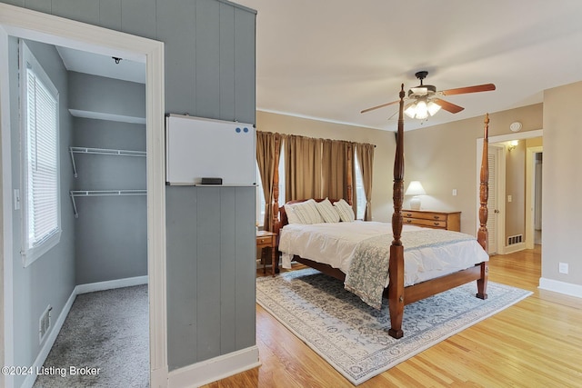 bedroom featuring multiple windows, wood-type flooring, ceiling fan, and a closet