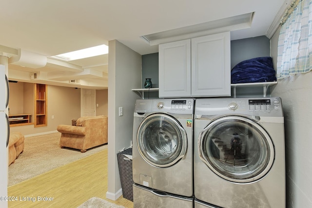 washroom with cabinets, light wood-type flooring, and separate washer and dryer