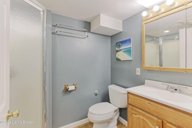 bathroom with vanity, hardwood / wood-style floors, a shower with shower door, and toilet