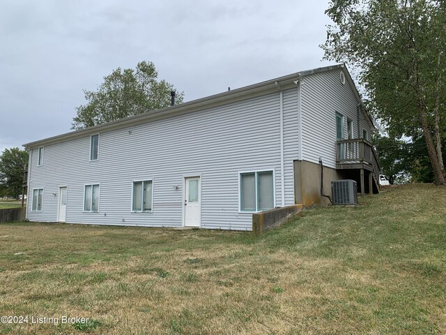 rear view of property with central AC unit and a yard