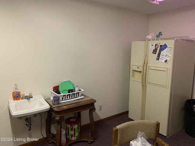 interior space featuring dark carpet, white refrigerator with ice dispenser, and sink