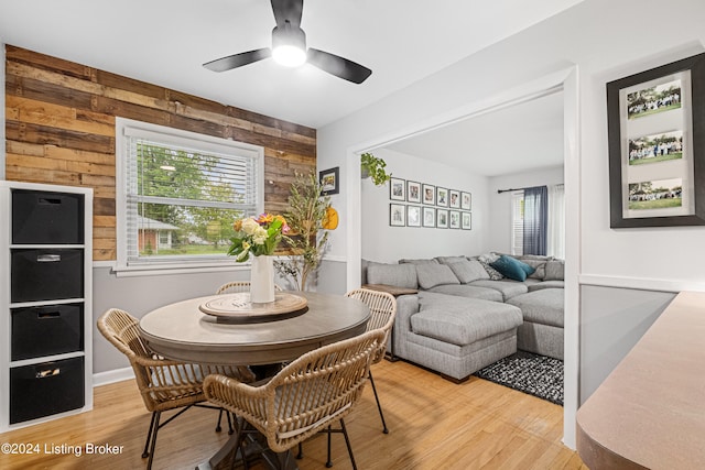 dining area featuring wood walls, ceiling fan, and light hardwood / wood-style flooring