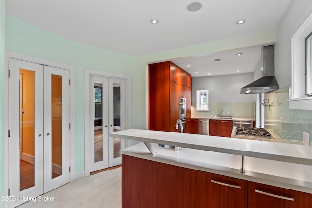 kitchen with french doors, stainless steel appliances, light wood-type flooring, and wall chimney range hood