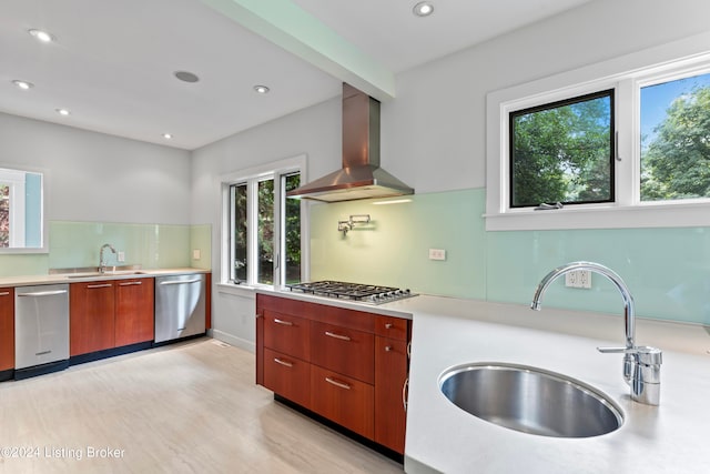 kitchen with wall chimney exhaust hood, light hardwood / wood-style floors, appliances with stainless steel finishes, and sink