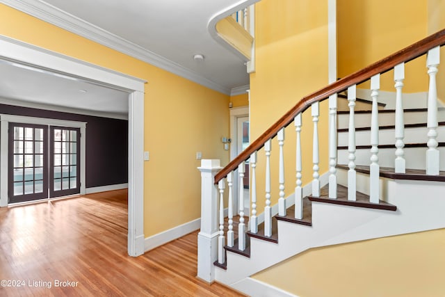 staircase with ornamental molding, hardwood / wood-style floors, and french doors